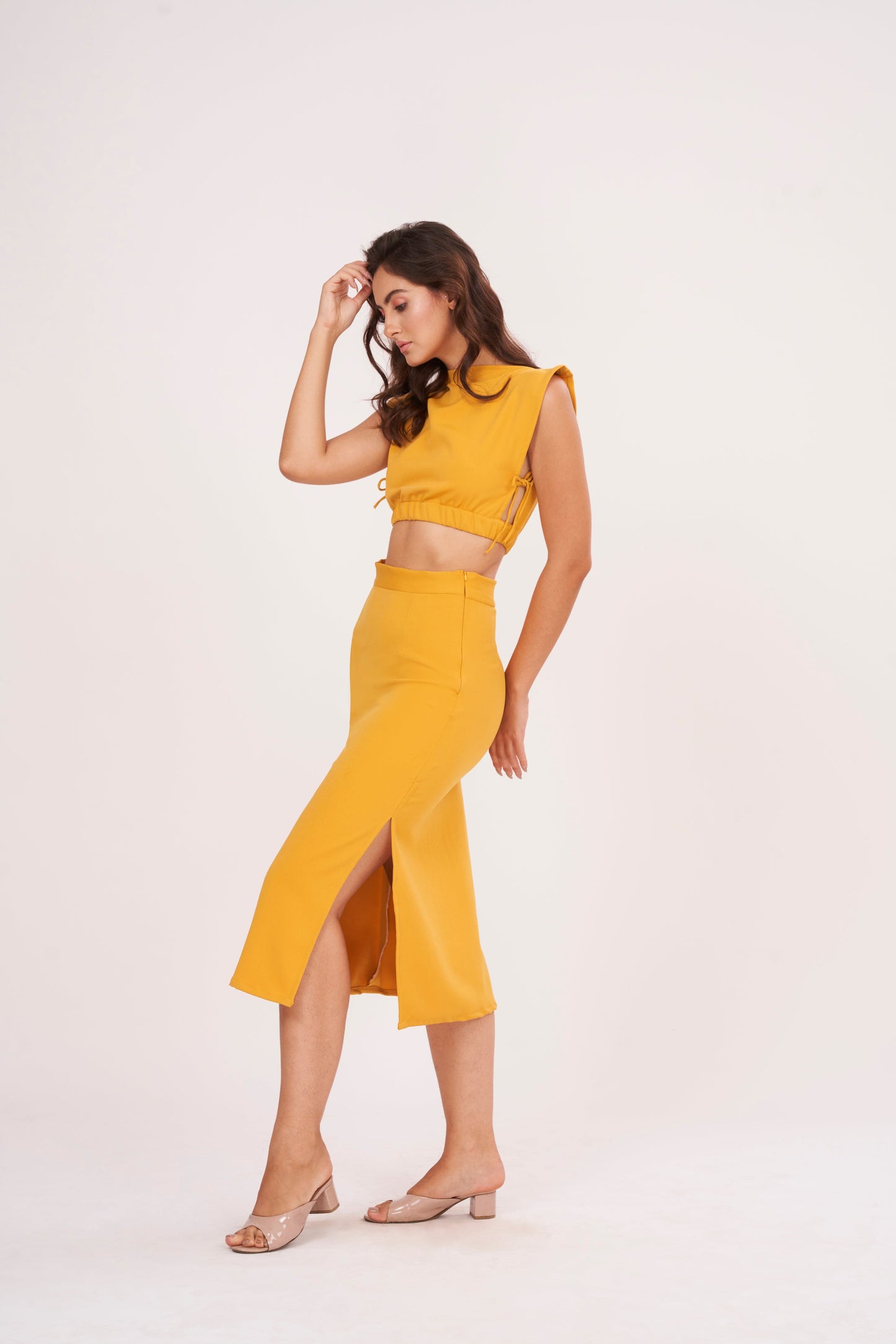 Mustard yellow long skirt with high-waisted design and side slit, made from high-quality muslin fabric. Side cut adds drama and allure. Suitable for dressing up or down.