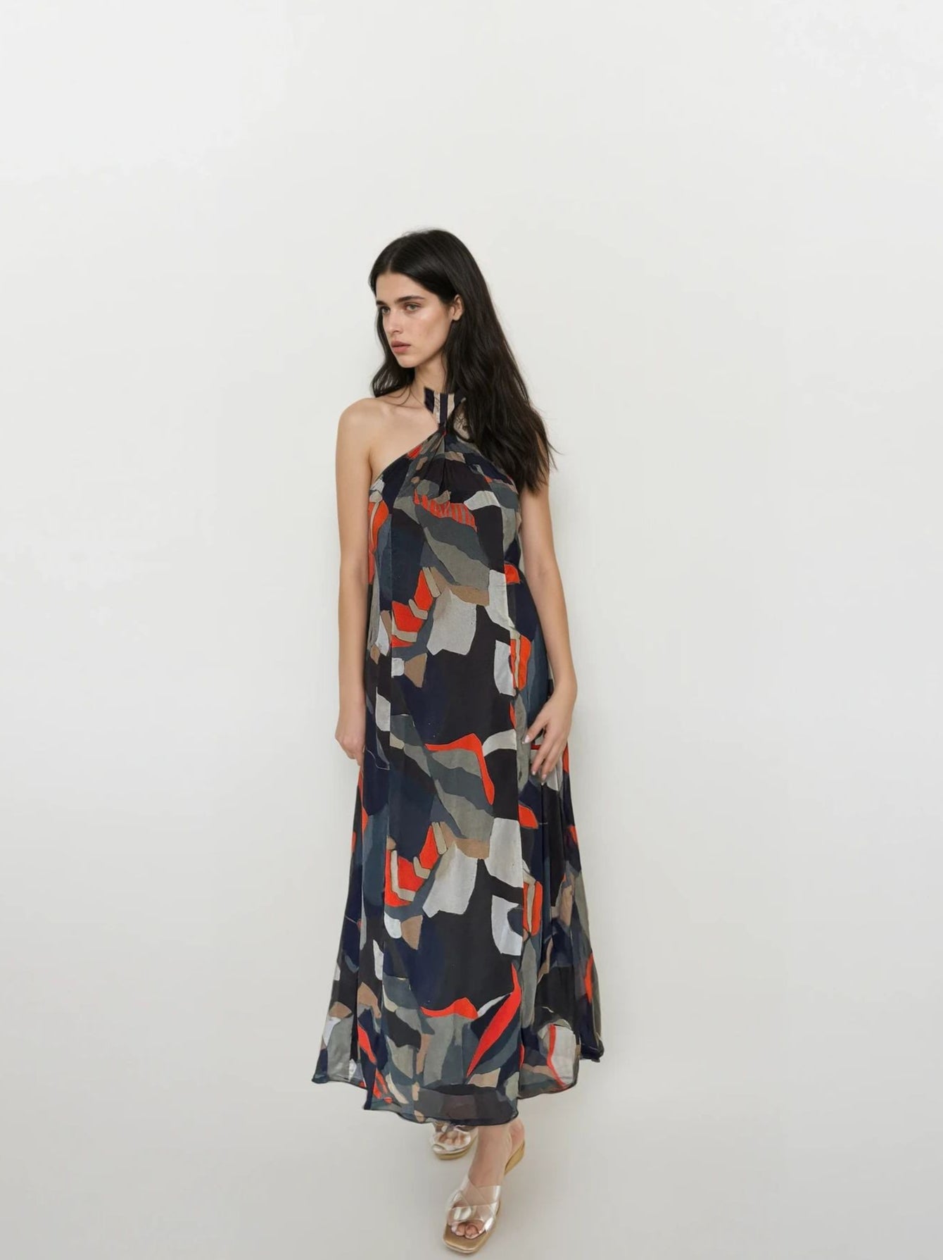 Flowy bohemian halter neck maxi dress featuring navy, olive, beige, and orange abstract pattern
