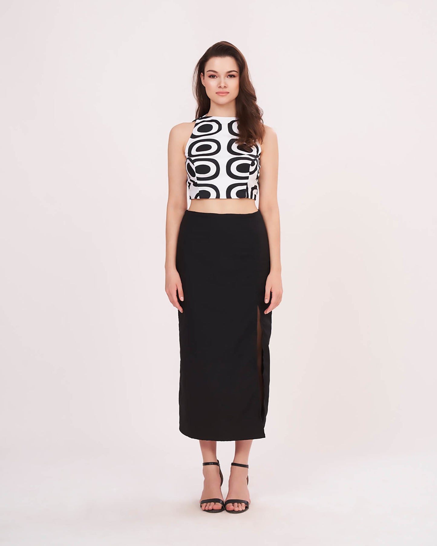 Relaxed standing pose with arms down, showcasing the high slit and length of the black solid skirt.