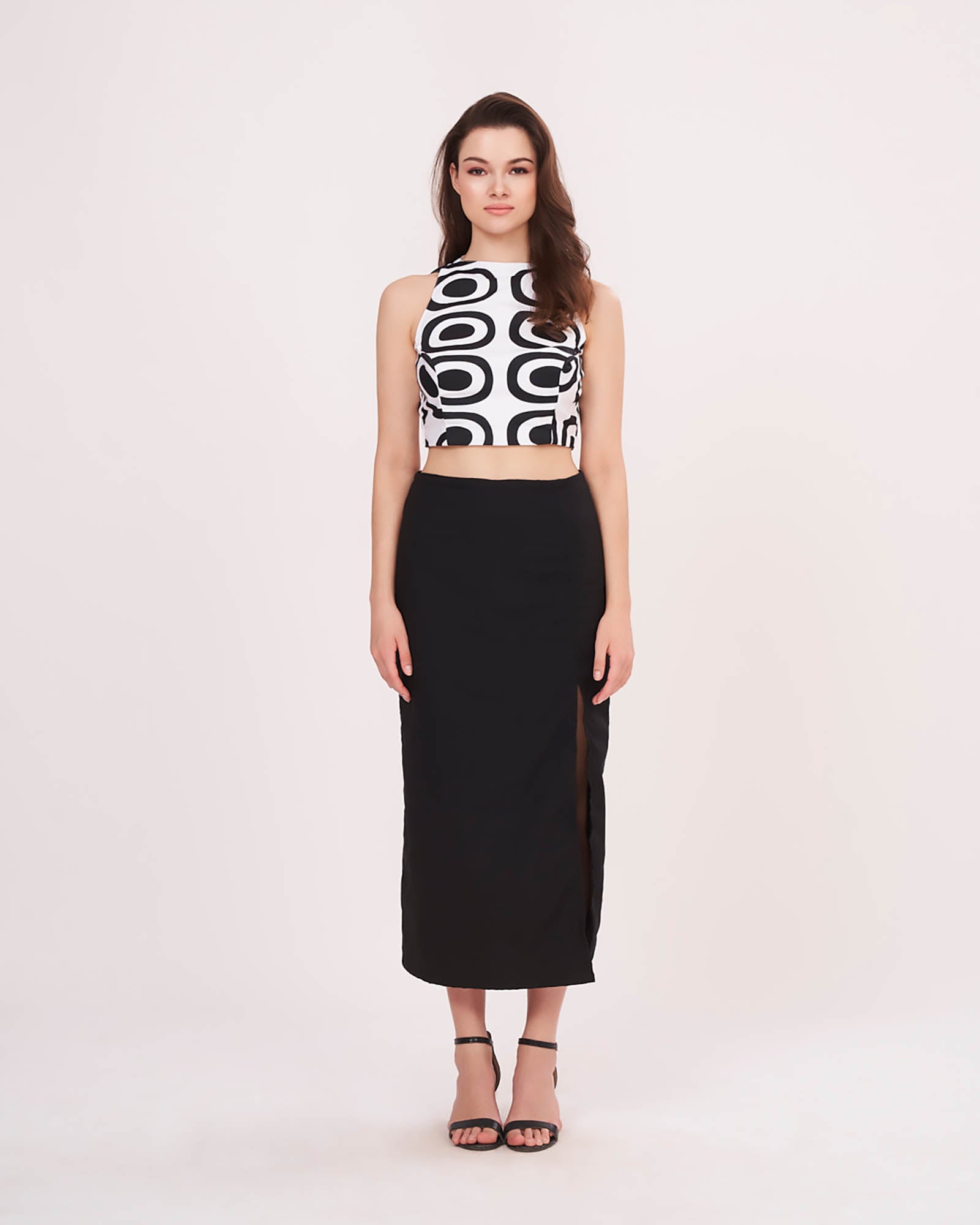Relaxed standing pose with arms down, showcasing the high slit and length of the black solid skirt.