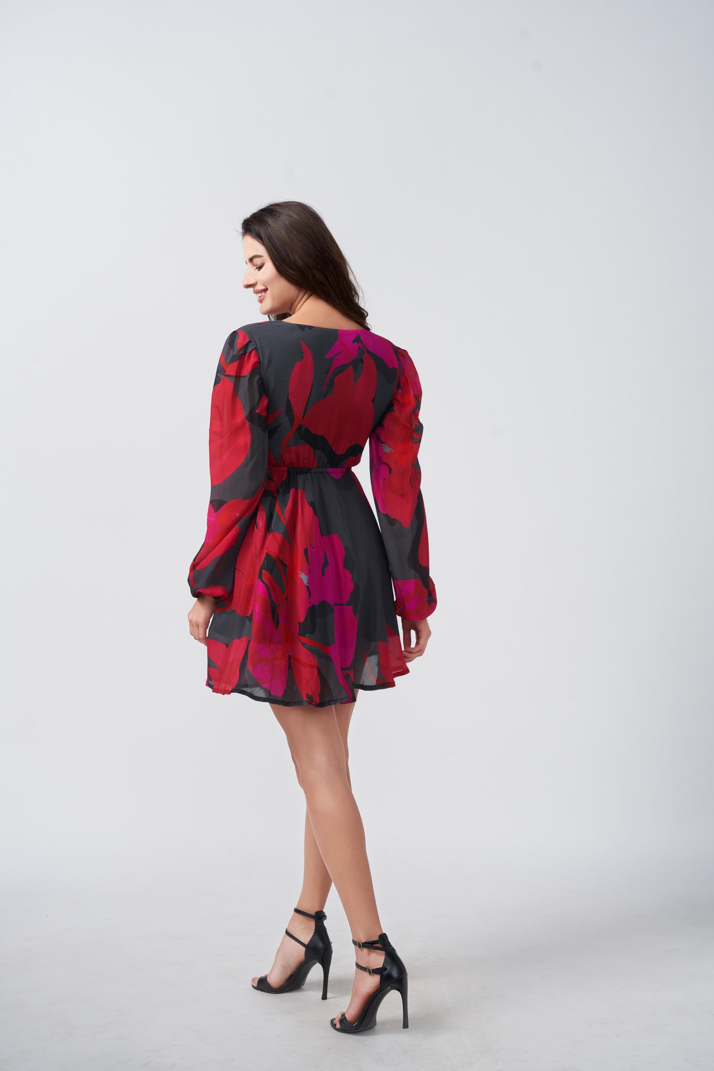 Rear side view of model in red and pink dress with long puff sleeves and a short hemline.