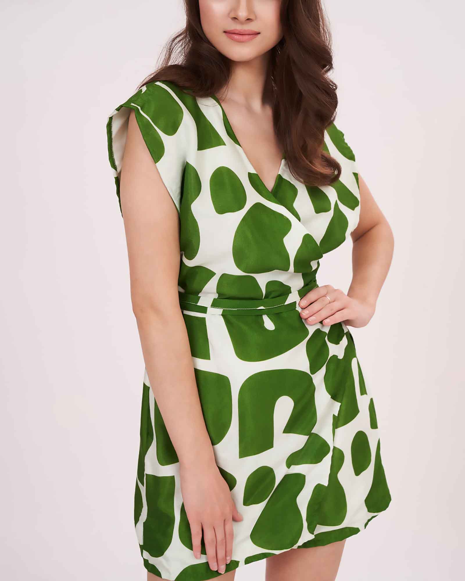 Side profile of green abstract sleeveless wrap dress with V-neck and cinched waist.