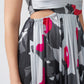 Close-up of waist cut and pleated skirt detailing on pink, grey, and charcoal abstract midi dress.