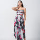 Model in grey, pink, and charcoal abstract print midi dress, posing with one hand near face in studio.