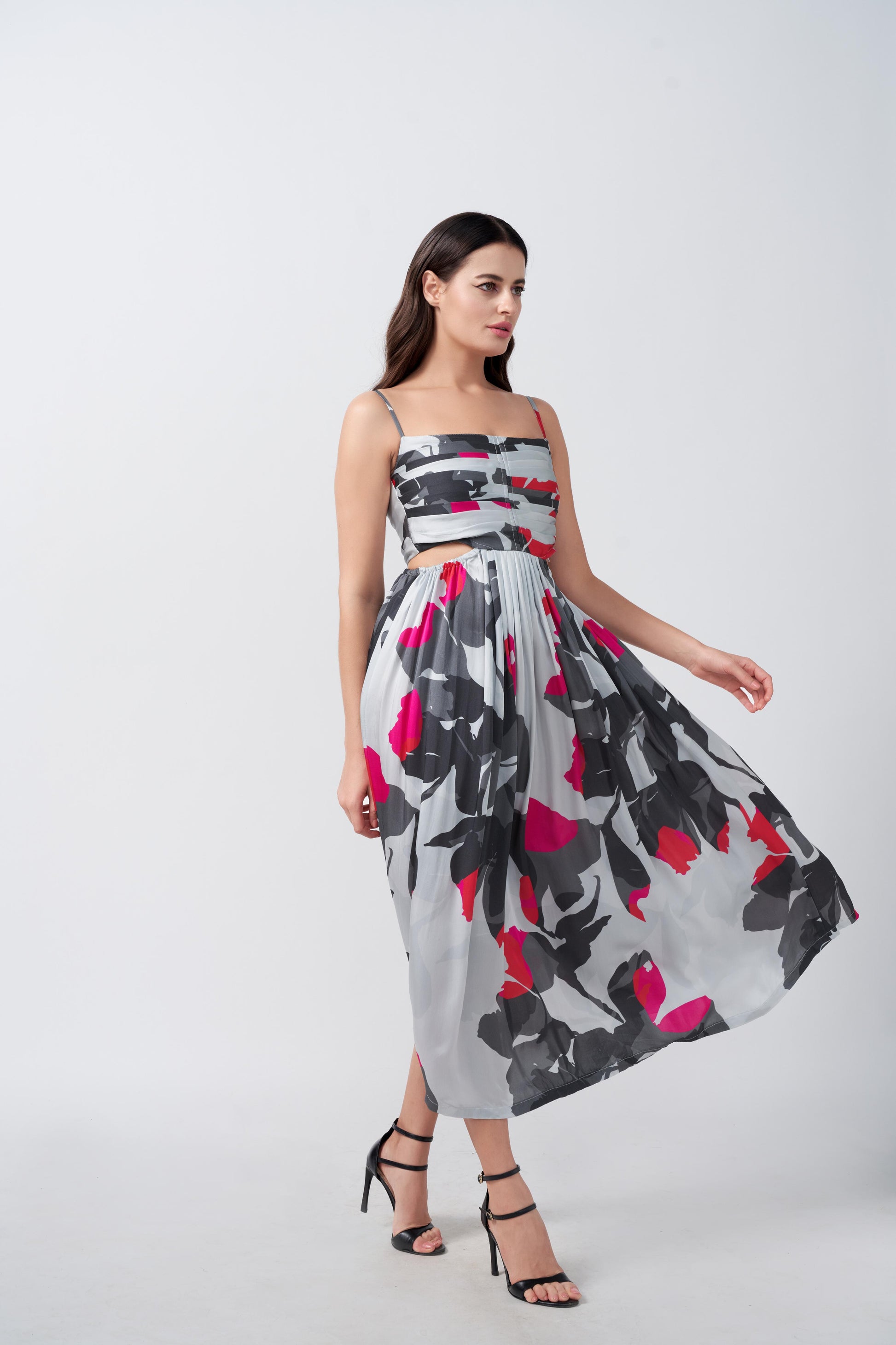 Side view of model twirling in pink and grey abstract midi dress, highlighting fluid A-line silhouette.