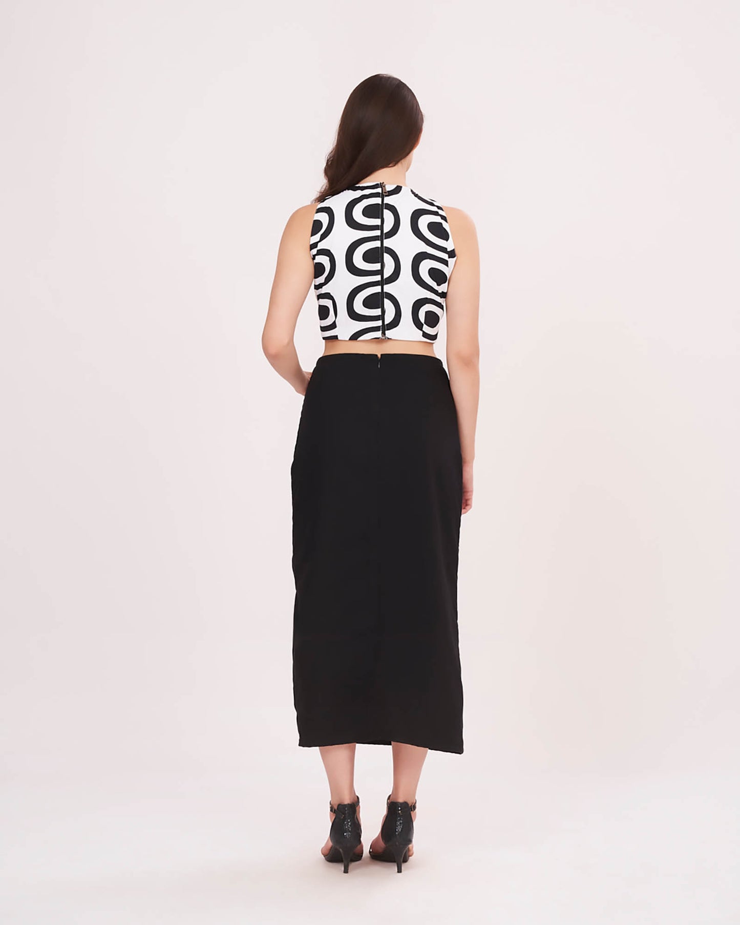 Rear view highlighting the halter neckline, zip closure, and minimalist back cut of the black skirt.