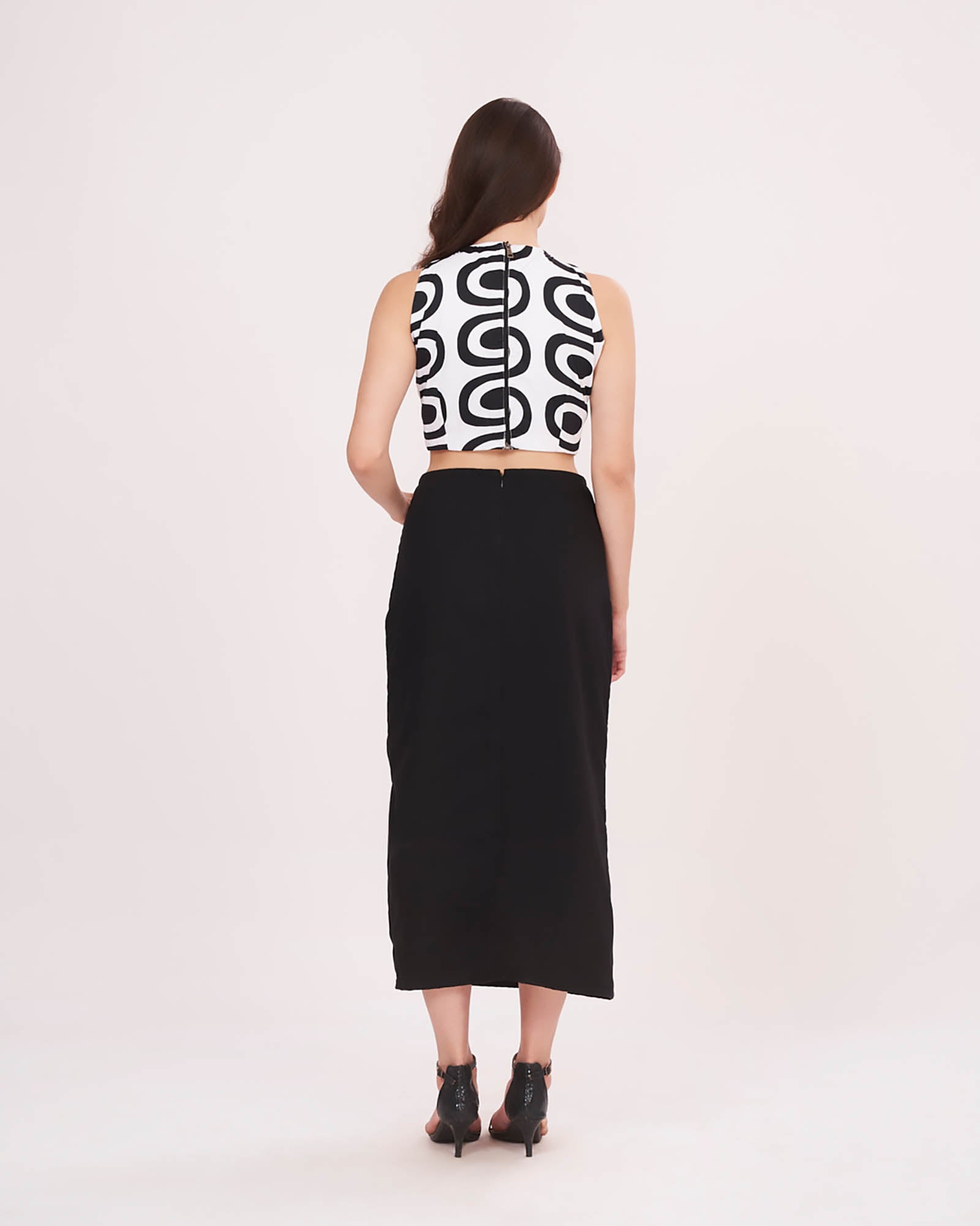 Rear view highlighting the halter neckline, zip closure, and minimalist back cut of the black skirt.