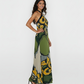 Elegant maxi gown with a fluid silhouette and a high, criss cross halter neckline that transitions into a low-cut back. The large-scale floral pattern is strategically placed to create visual movement, ideal for vacation dinners or high-end resort wear.