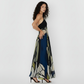 Sleeveless maxi dress emphasizing the intricate detail of its "Olive Dusk" print, which features organic shapes and soft, blurred outlines. The dress is crafted from a high-quality, breathable crepe fabric designed to offer comfort and movement for high-end summer celebrations.
