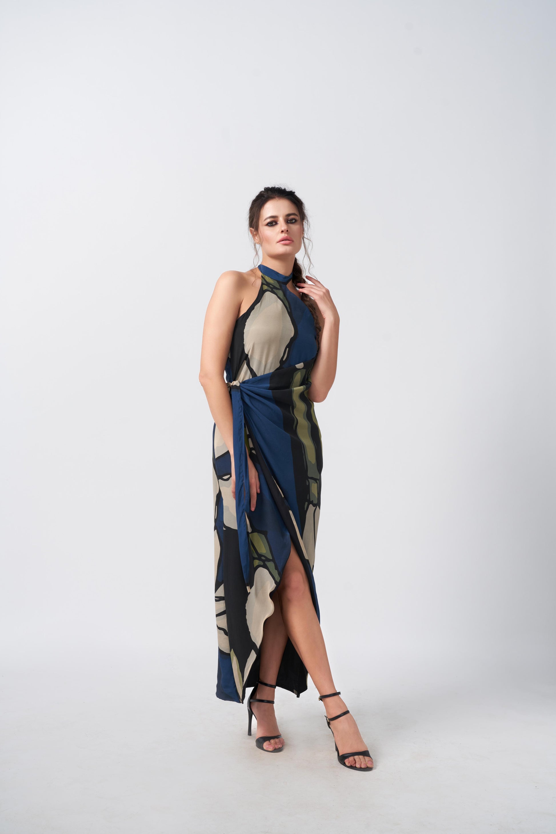 Model standing in full-length view of wrap style crepe dress with high halter neckline and geometric print.