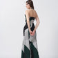 Rear view of model walking in green and grey abstract printed halter dress with tie-back and ankle length cut.