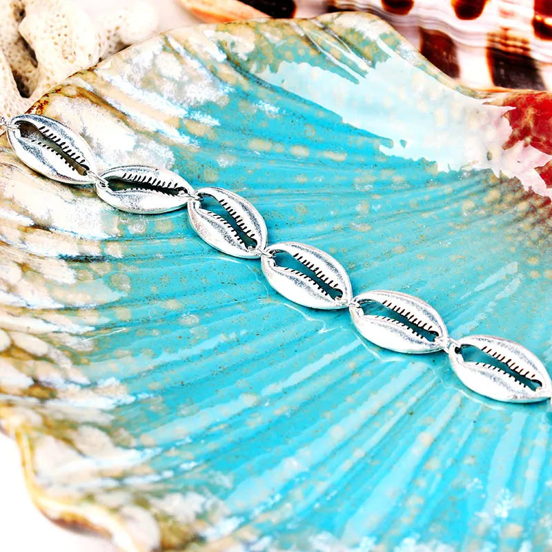 This elegant silver-toned shell anklet captures a modern coastal aesthetic, making it a versatile piece to pair with your favorite sandals or holiday attire.