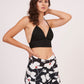Deep V-neck bralette top contrasting with large white and red botanical motifs for a striking vacation look.