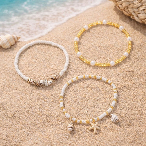 A beautiful three-piece anklet set featuring a mix of turquoise beads, a gold starfish charm, and a natural cowrie shell.