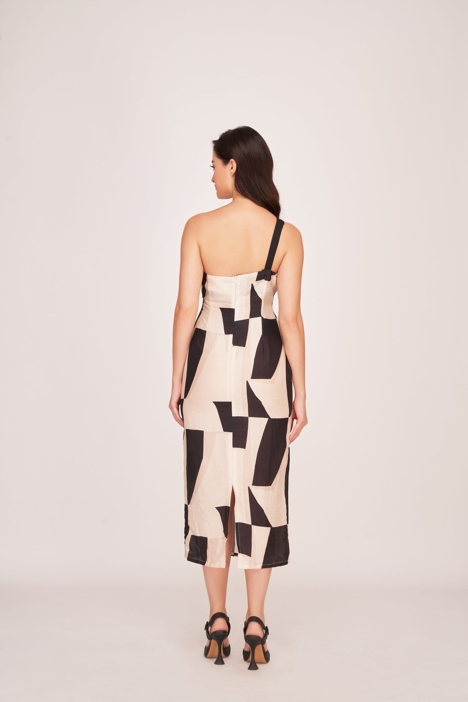 Rear view of the model in the one-shoulder abstract print dress, highlighting the back zip closure and silhouette.