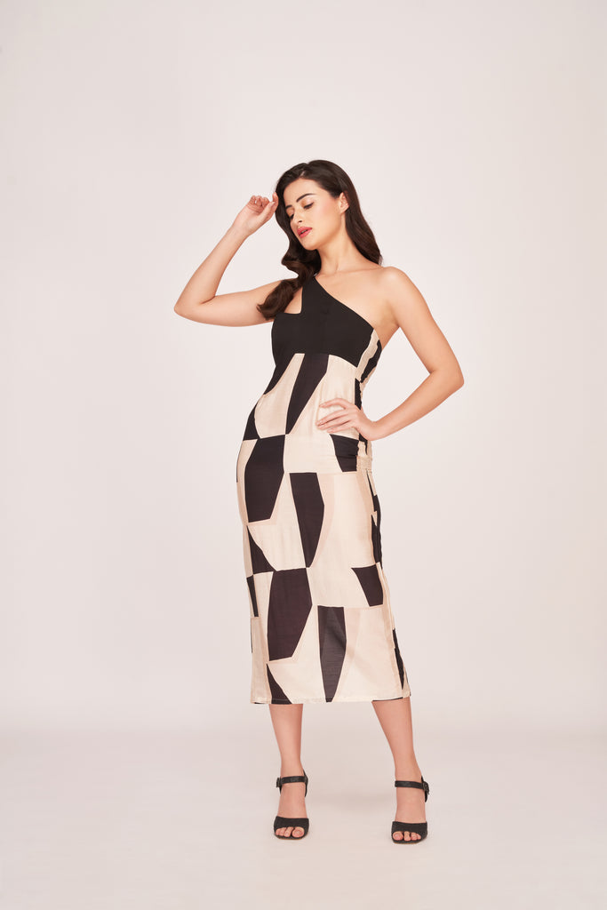 Model posing confidently in a black and white abstract print one-shoulder silk midi dress against a plain backdrop.