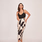 Model wearing a black abstract printed sleeveless satin midi dress with V-neckline and side cut-outs, posing front-facing.