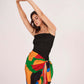 Playful standing pose with both arms overhead, showcasing the fitted silhouette of the black dress and asymmetric sarong tie-up.