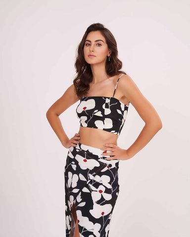 Model poses with hands on waist, showcasing the strap shoulder black floral crop top and matching wrap skirt.