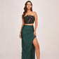 A glamorous co-ord set pairing a shimmering black crop top with a floor-length forest green skirt featuring a daring thigh-high slit.