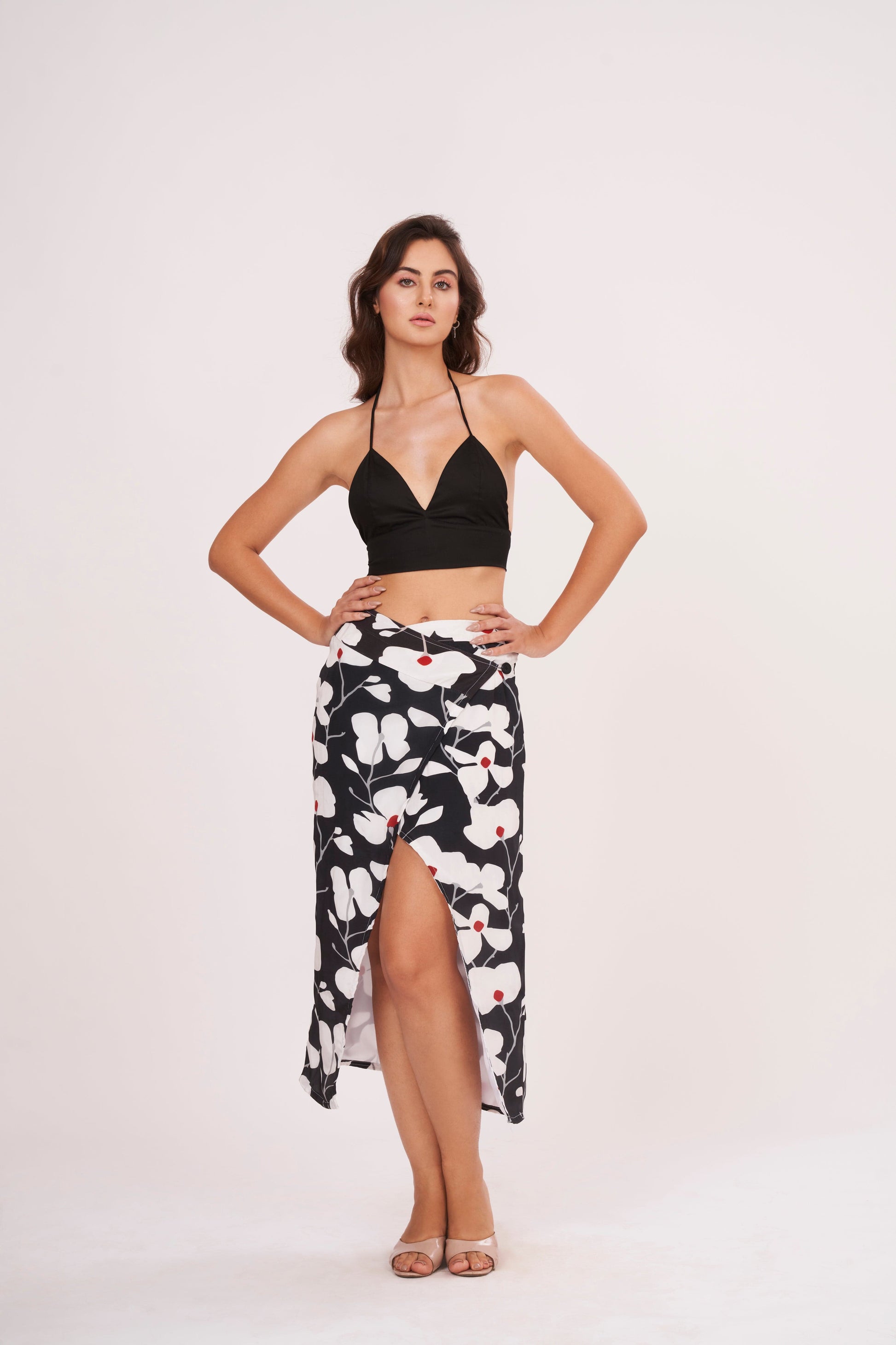 Black halter-neck crop top paired with a midi skirt featuring a bold white floral print on a black background.