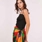 Model in close-up front-facing pose showcasing the square-neck black mini dress and vibrant sarong tied at the waist.