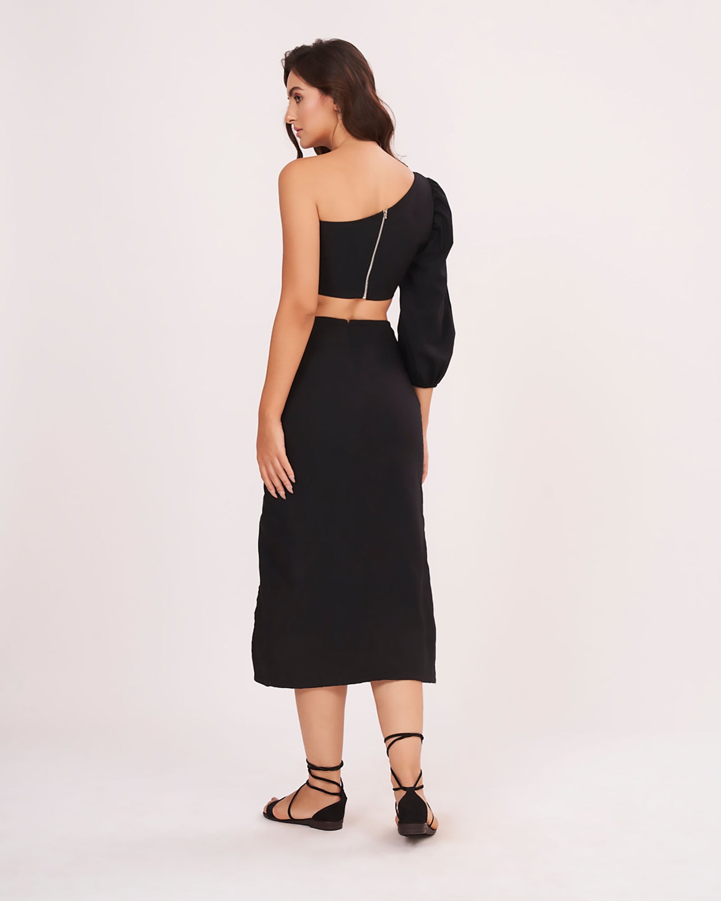 Rear view displaying the back zip closure and full-length flow of the solid black skirt.