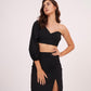 Model with hand on waist, showcasing the black one-sleeve crop top and thigh-high slit skirt.