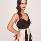Close-up of model in abstract print midi dress with pleated front yoke and V-neckline, hands on waist.