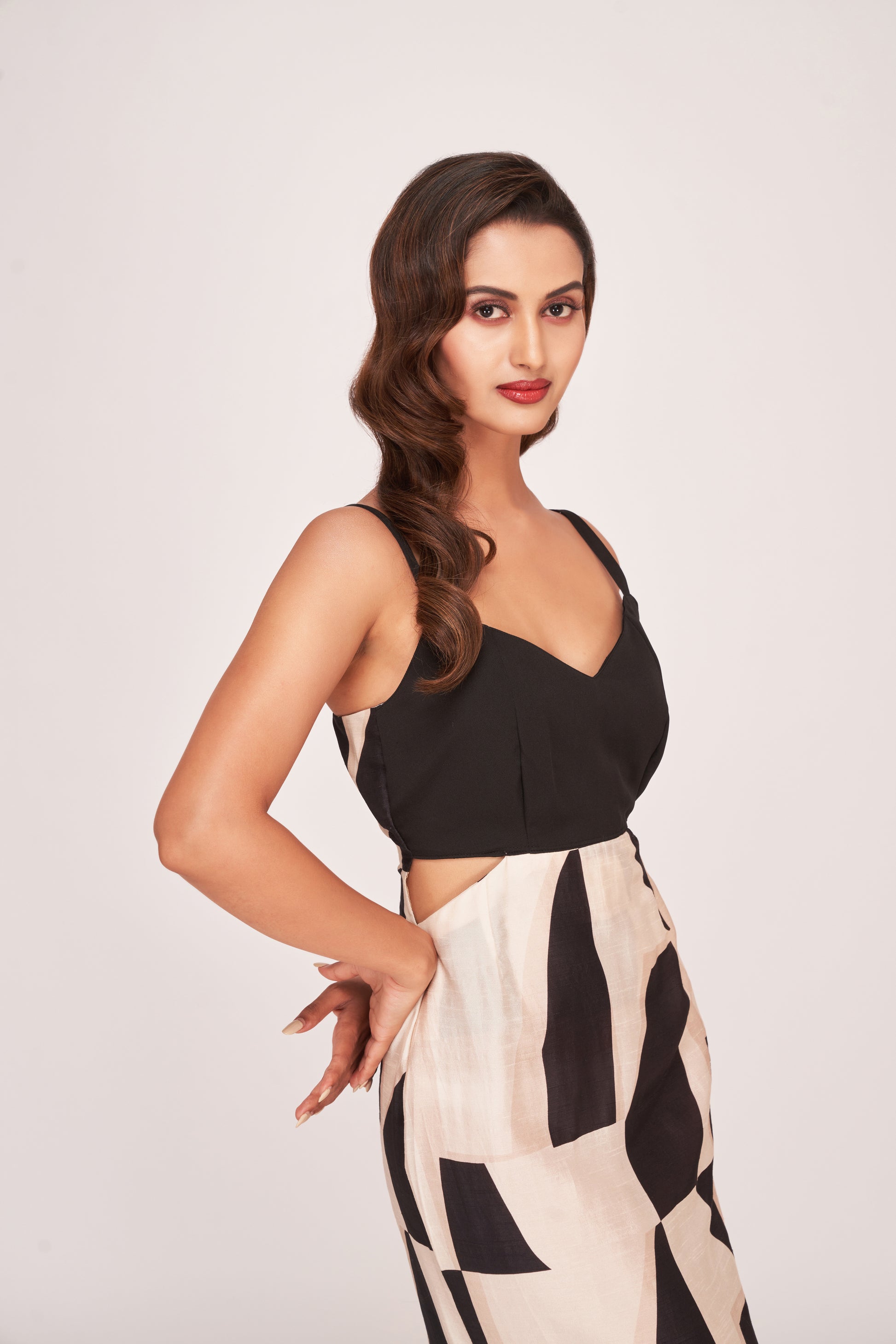 Close-up of model in abstract print midi dress with pleated front yoke and V-neckline, hands on waist.