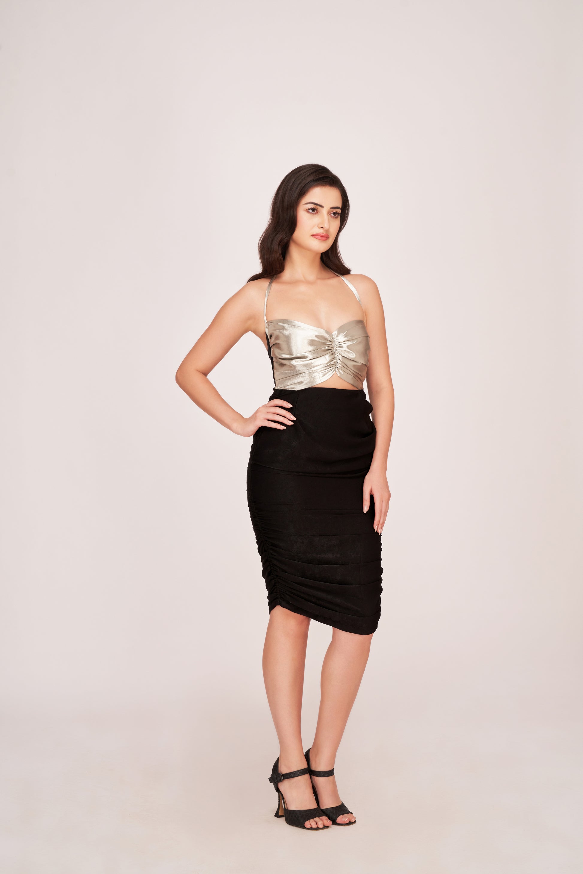 Model in a black and silver satin ruched dress with sweetheart neckline and strap shoulders, posing confidently.