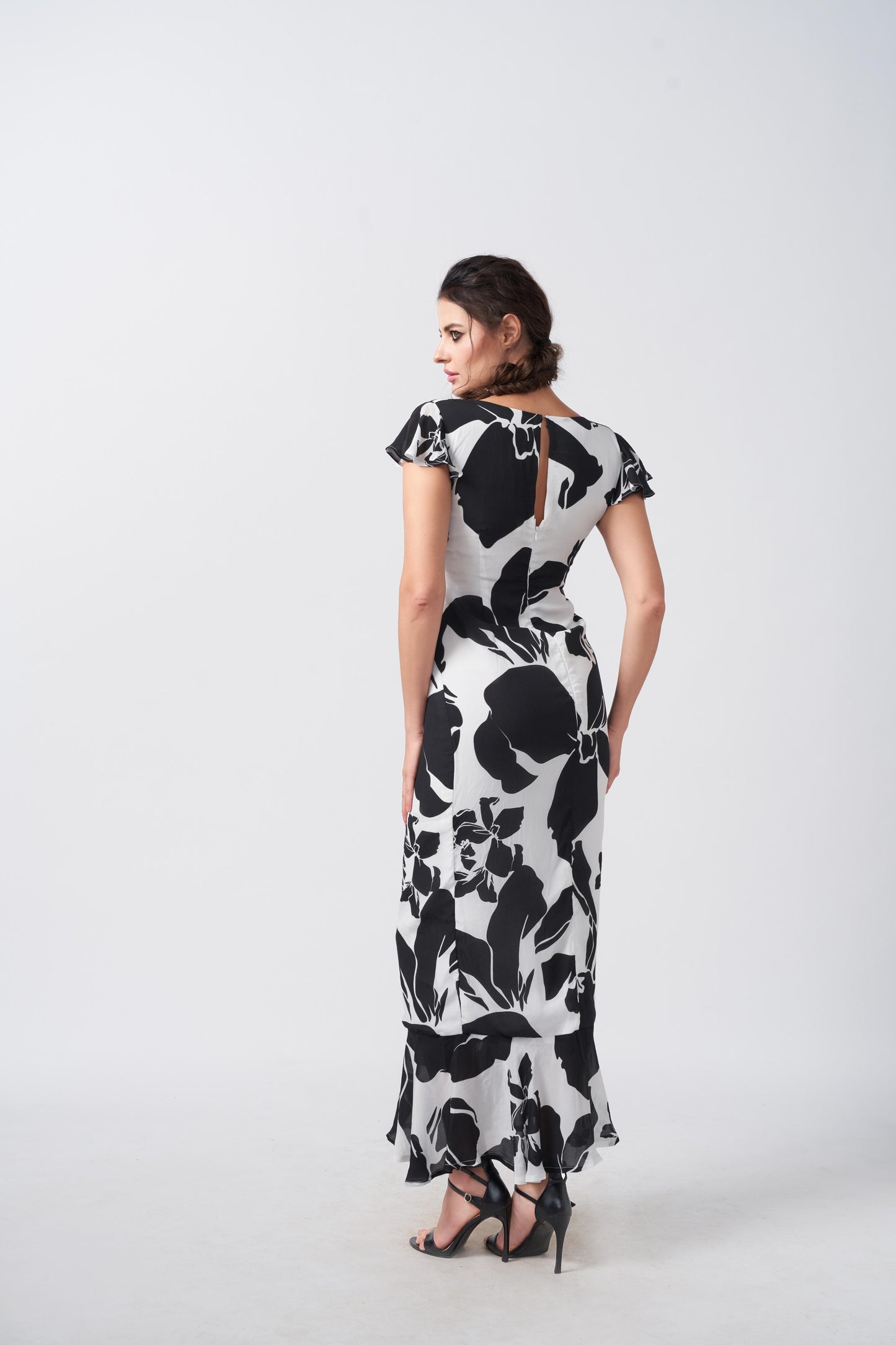 Back view of the model in ankle-length black and white abstract floral crepe dress.