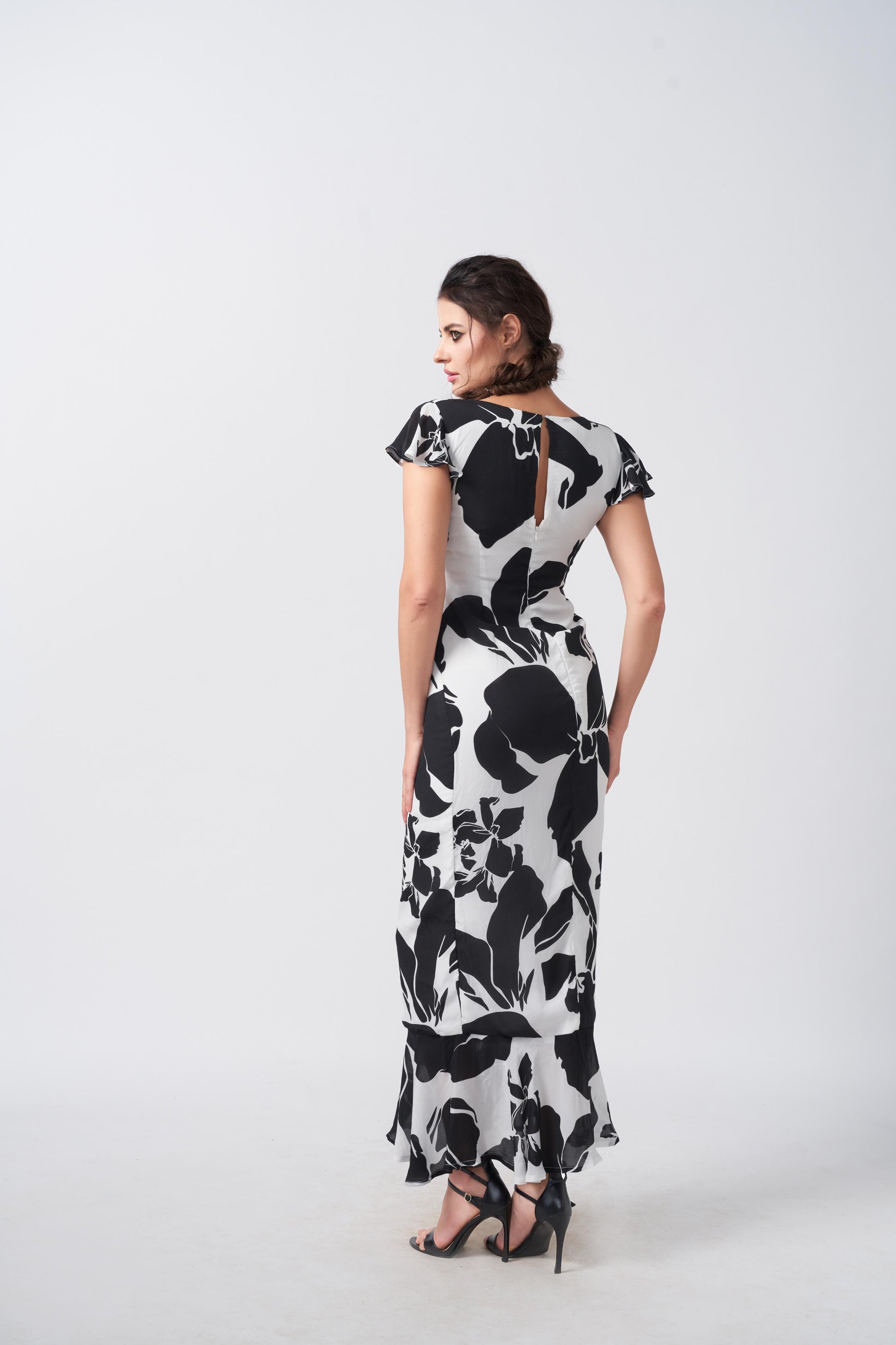 Back view of the model in ankle-length black and white abstract floral crepe dress.