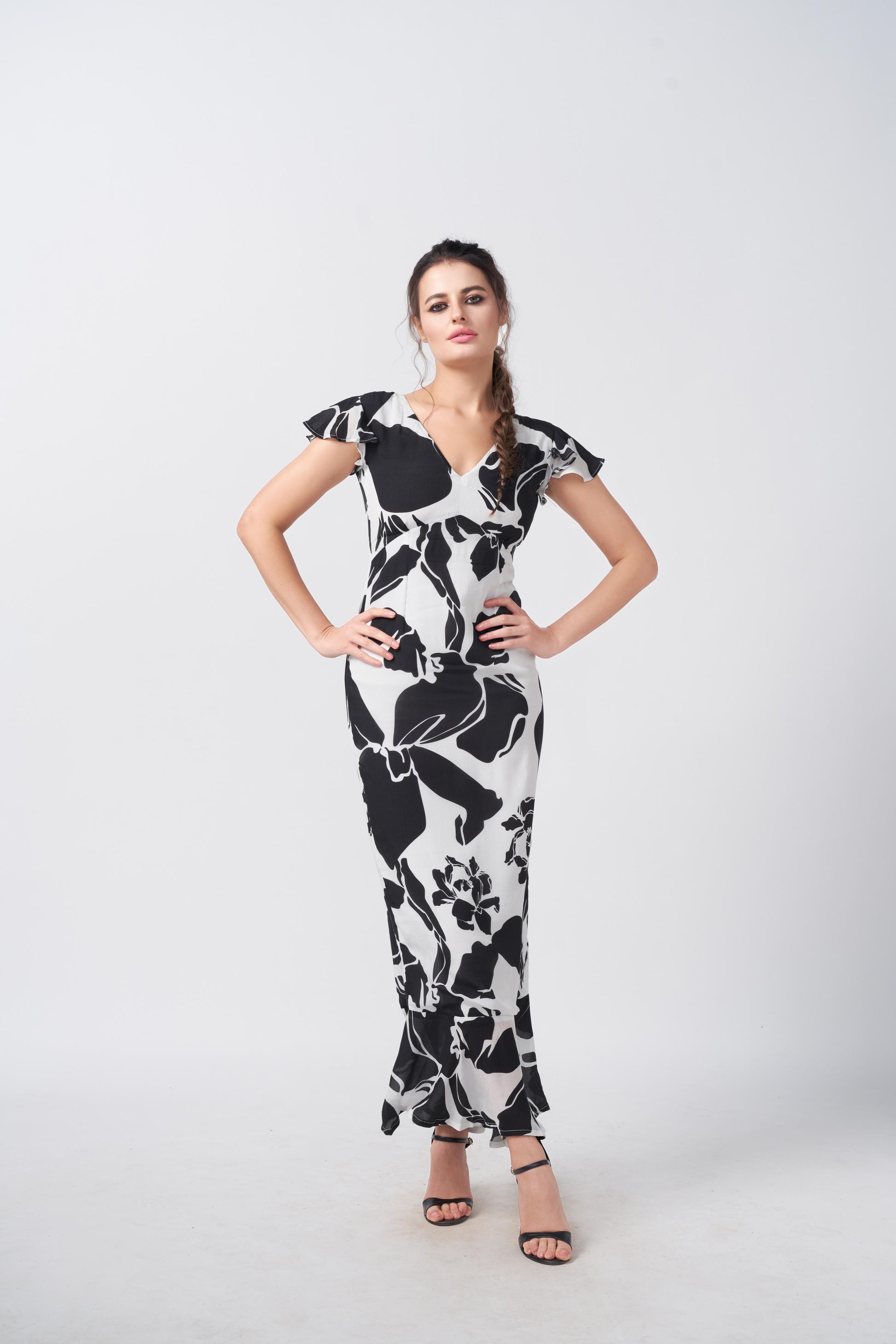 Model posing hands-on-hips, showcasing full silhouette of ankle-length floral crepe dress.