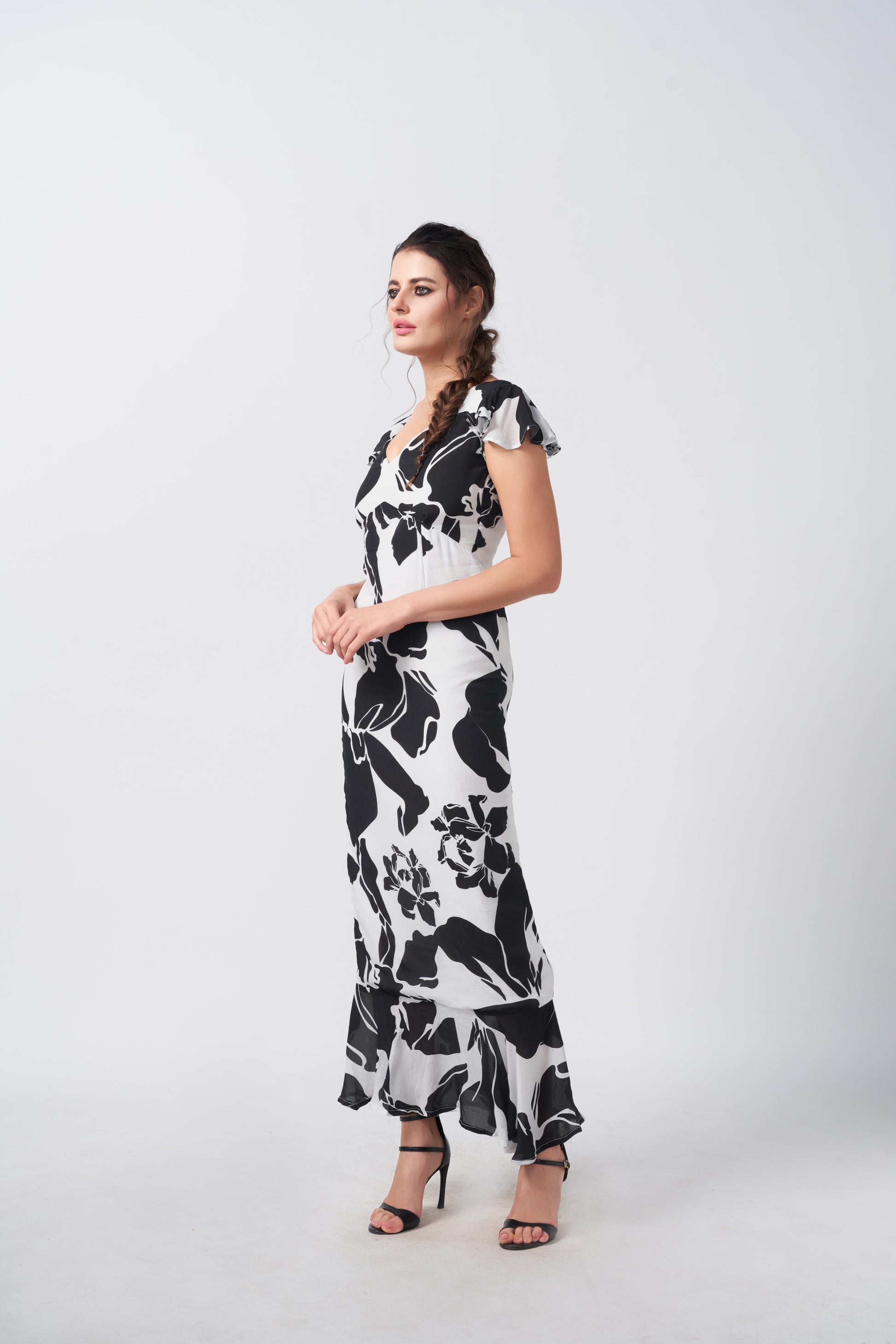 Side angle of the model in black and white abstract floral dress, highlighting elegant drape.