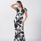 Model standing with hand on head in black and white floral crepe dress with V-neck and ruffle sleeves.