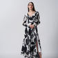 Model facing front in black and white floral crepe dress with V-neck and long sleeves.