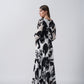 Model in side pose highlighting the side slit and sleeve drape of the black and white floral dress.