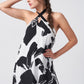 Close-up of the model in halter dress with hand on head, emphasizing neckline and bold abstract pattern.