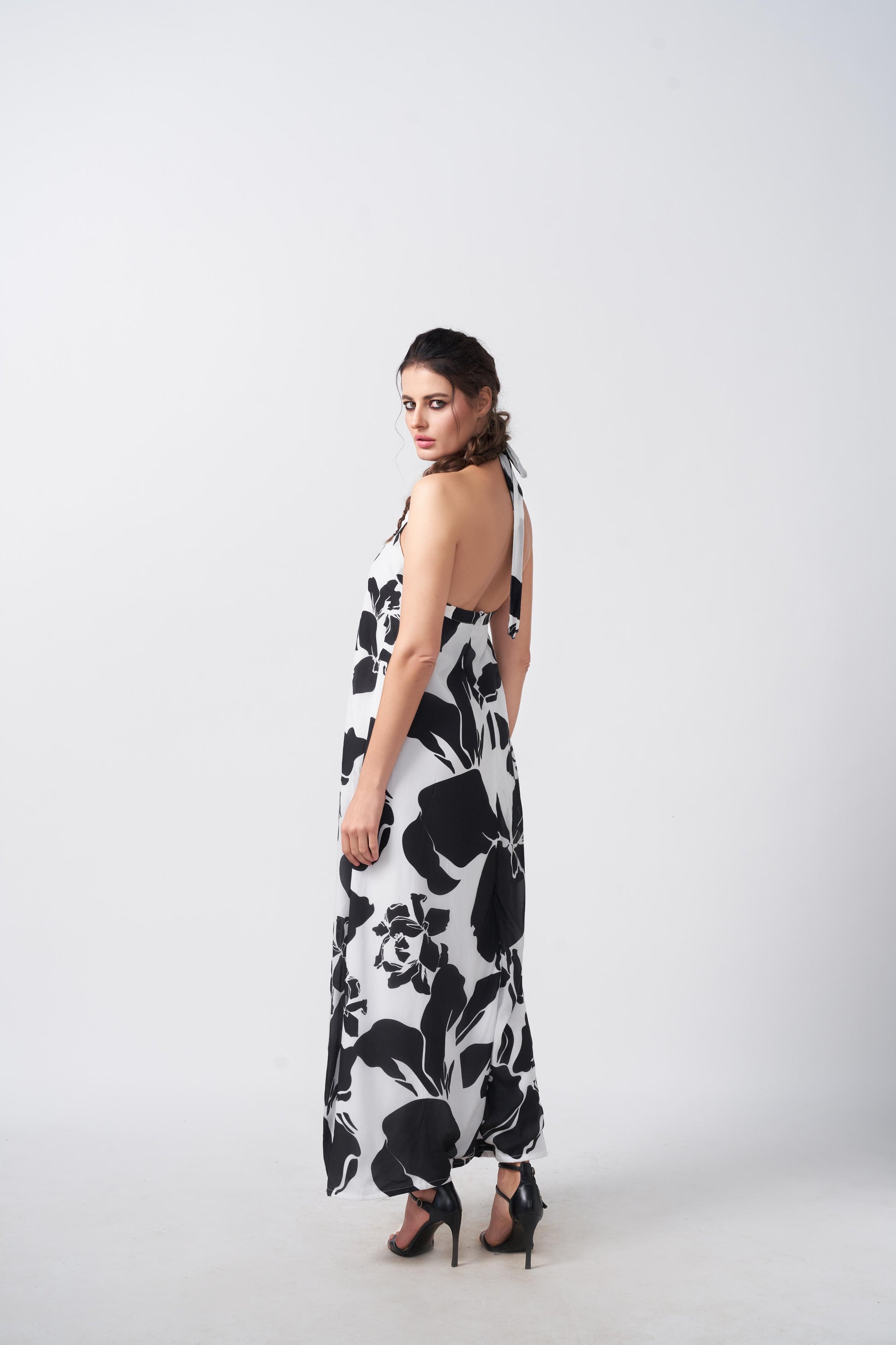 Side view of the model in black and white floral dress, showcasing the flow and tie-back halter neck.