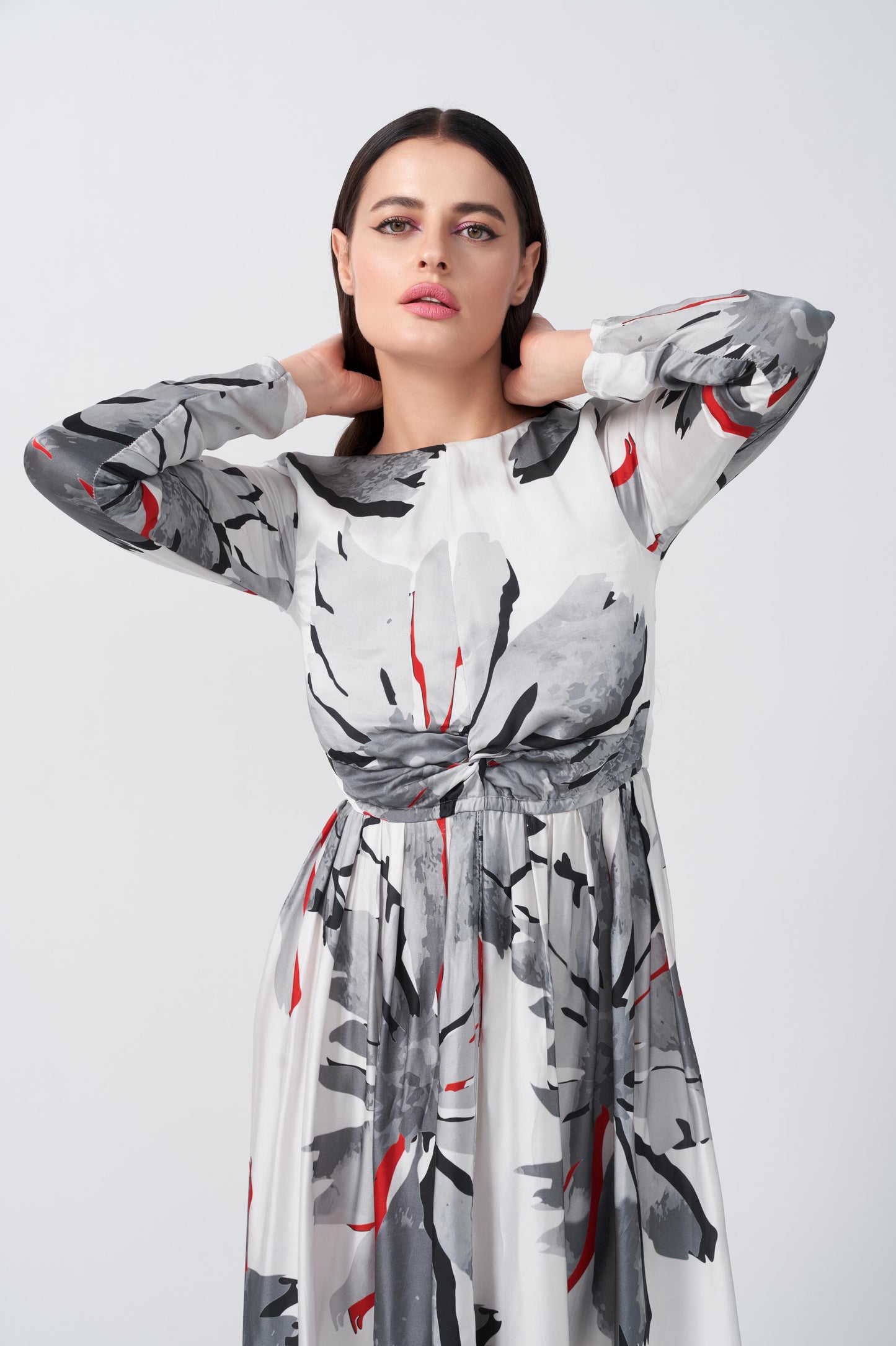  Model with arms raised, highlighting the bateau neckline and knot detail of the floral satin dress.