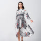 Model walking in a white and grey satin floral dress with red accents and knot front detail.