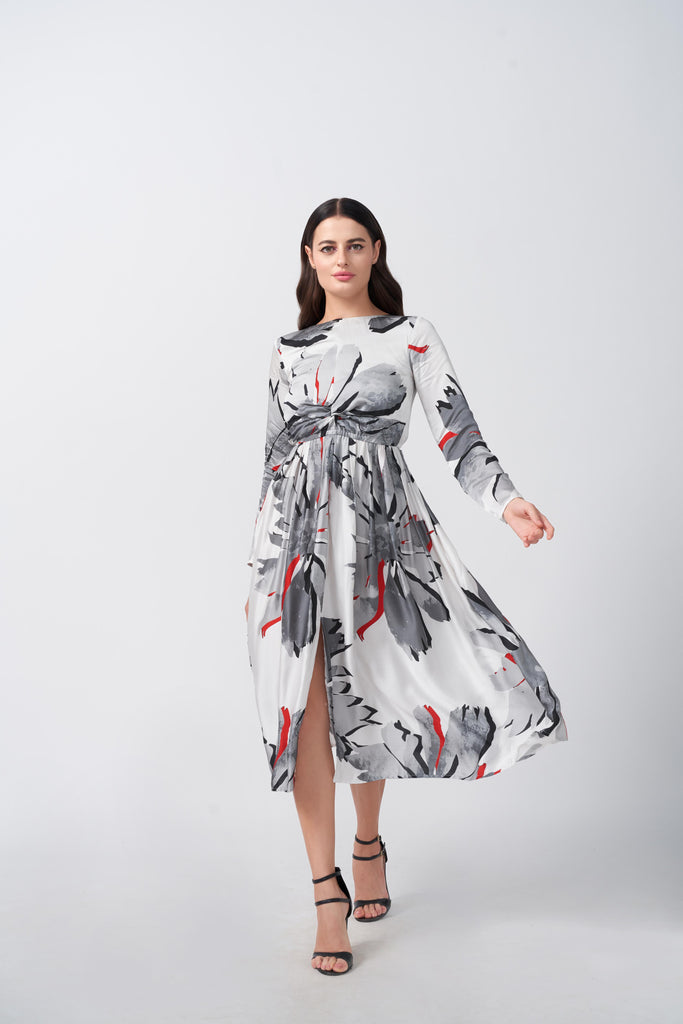 Model walking in a white and grey satin floral dress with red accents and knot front detail.