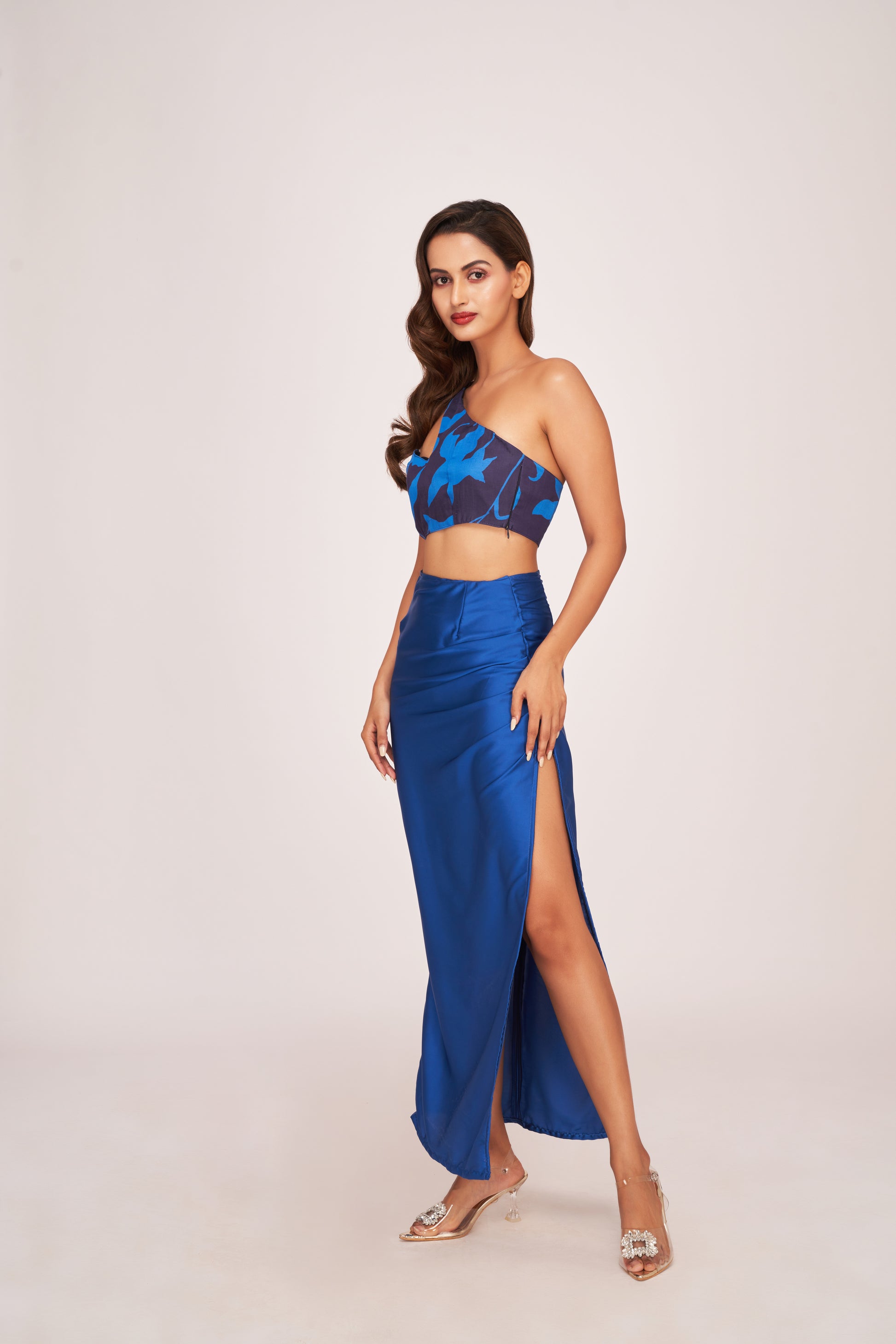 Model in mid-step pose flaunting the blue satin co-ord set, highlighting the flow of the slit skirt and cropped top.