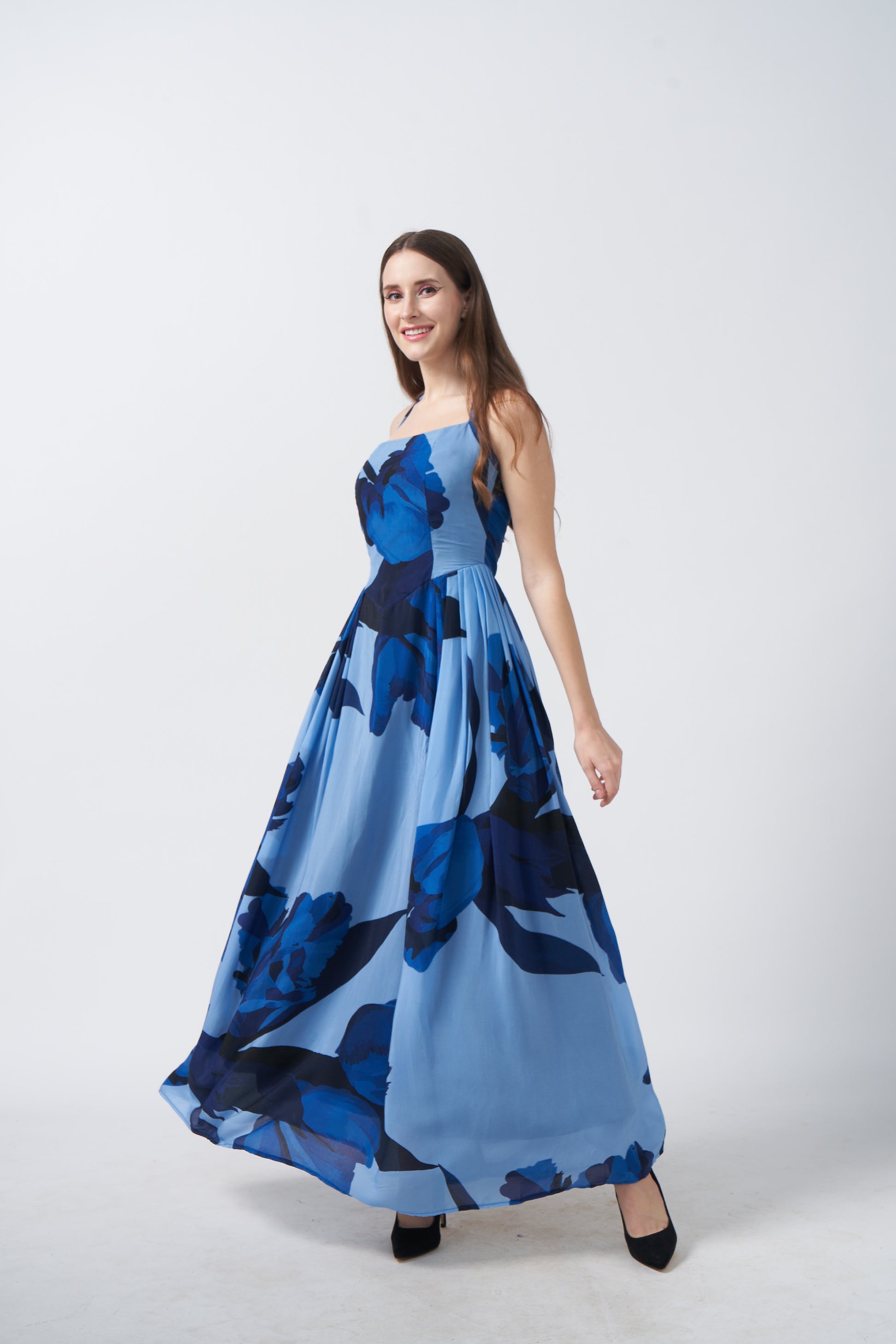 Side profile of model in halter neck blue floral crepe dress, highlighting the tie-back detail and flowy fabric.