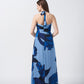 Back view of model in blue floral crepe halter dress, featuring tie-back neckline and fluid drape.