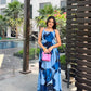 Model walking outdoors in blue floral ankle-length dress with halter tie-back neck, capturing effortless elegance.