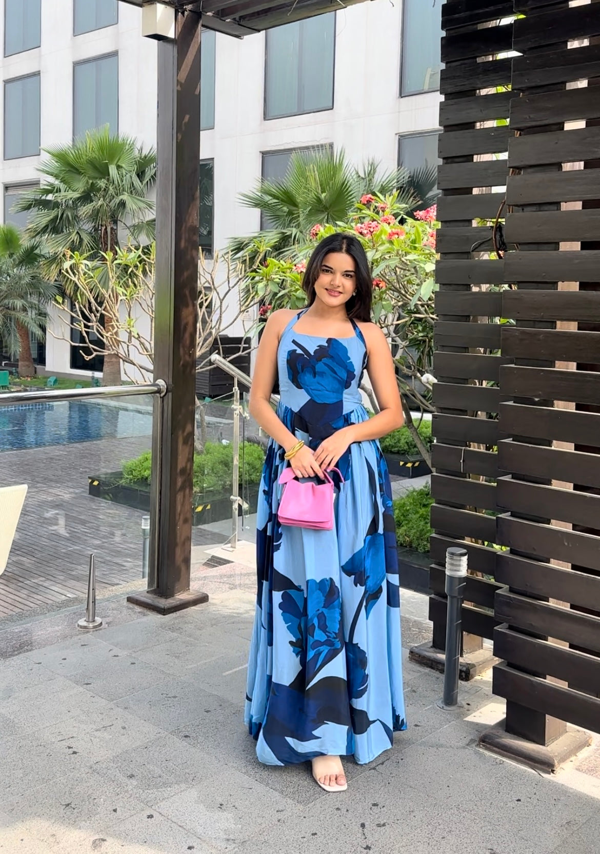 Model walking outdoors in blue floral ankle-length dress with halter tie-back neck, capturing effortless elegance.