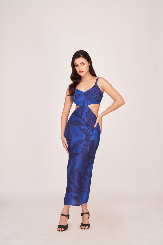 Model wearing a blue floral silk midi dress with V-neck and side cut-outs, posing front-facing with hands on hips.