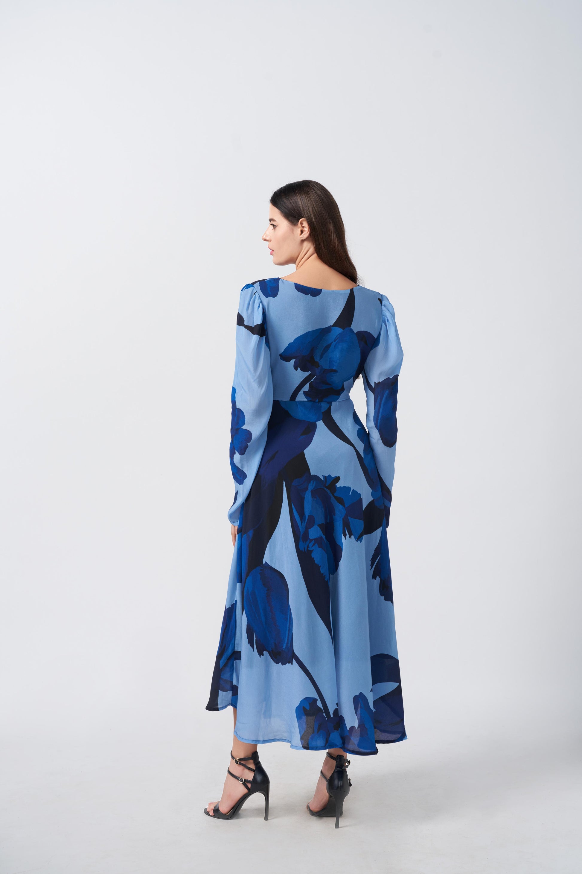 Back view of the model in blue floral dress, showcasing flowy silhouette and full sleeve coverage.